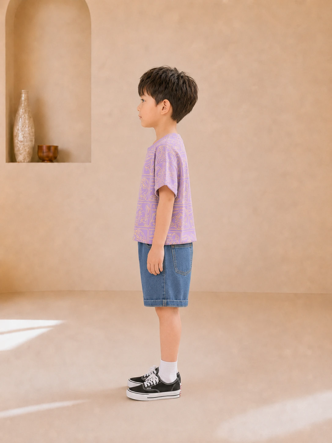 Boy wearing a purple dinosaur-print T-shirt and blue denim shorts