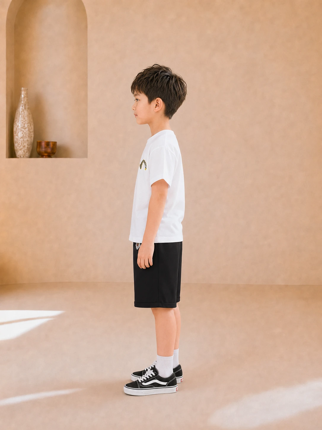 Boy wearing a white graphic T-shirt and black knee-length shorts