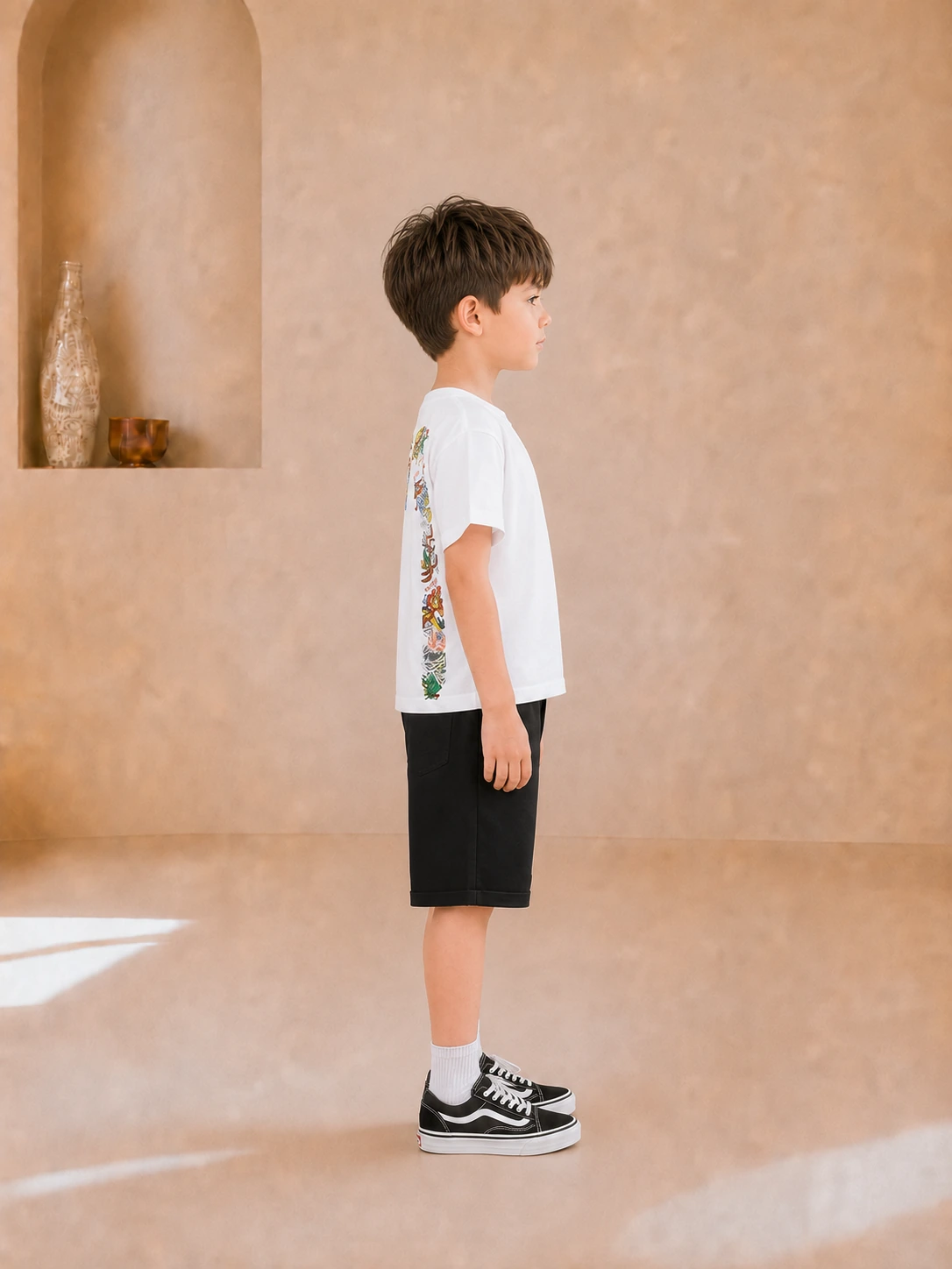 Boy wearing a white graphic T-shirt and black knee-length shorts