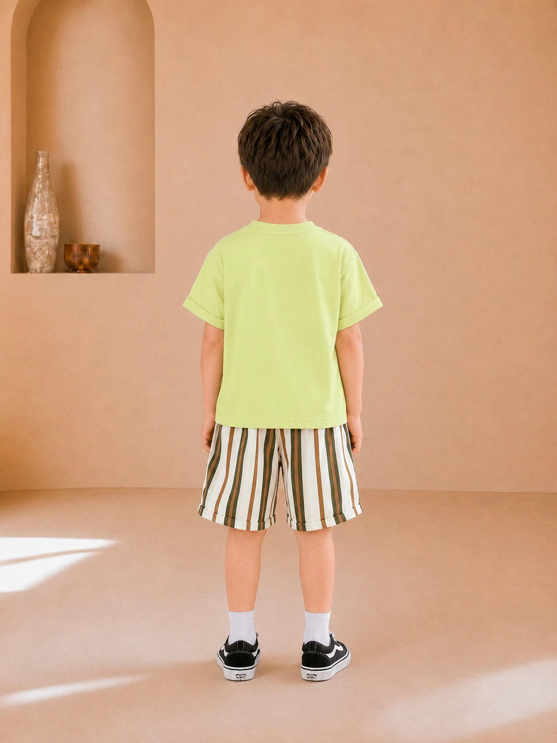 Boy wearing a lime green graphic T-shirt and striped knee-length shorts