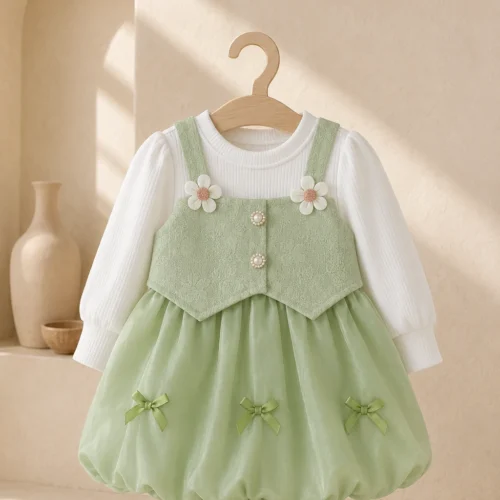 Girl wearing a green pinafore party dress with a white long-sleeve top