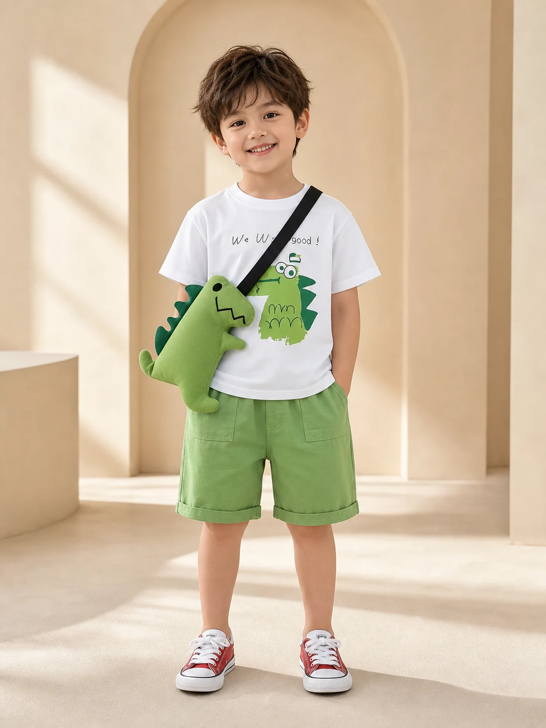 Boy wearing a white dinosaur T-shirt, green shorts and dinosaur crossbody bag