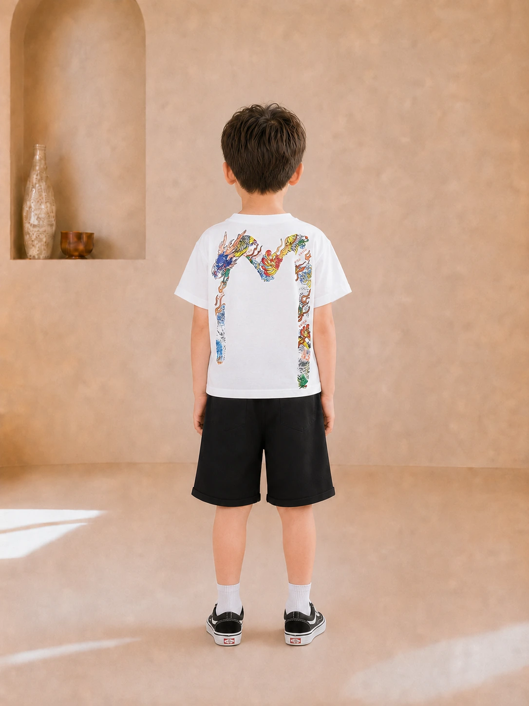 Boy wearing a white graphic T-shirt and black knee-length shorts