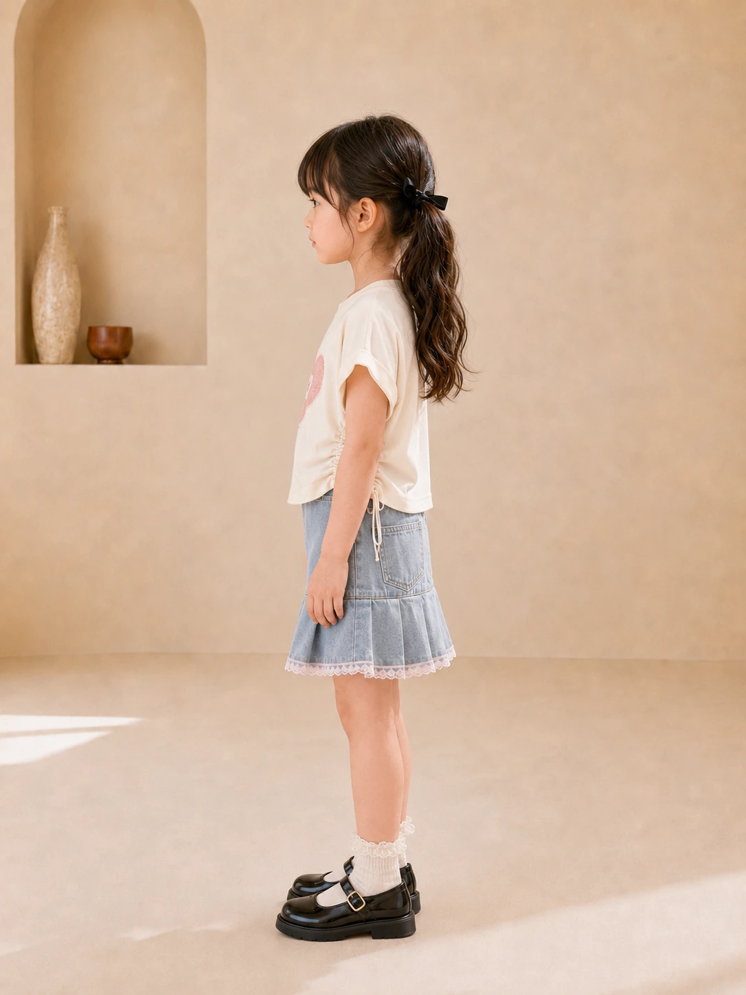 Girl wearing a white heart-print top and blue denim pleated skirt