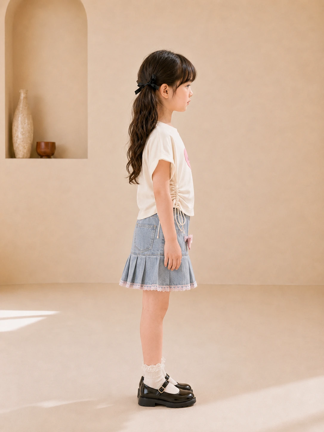 Girl wearing a white heart-print top and blue denim pleated skirt