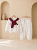 Girl wearing a cream sweatshirt and jogger set with burgundy scarf detail