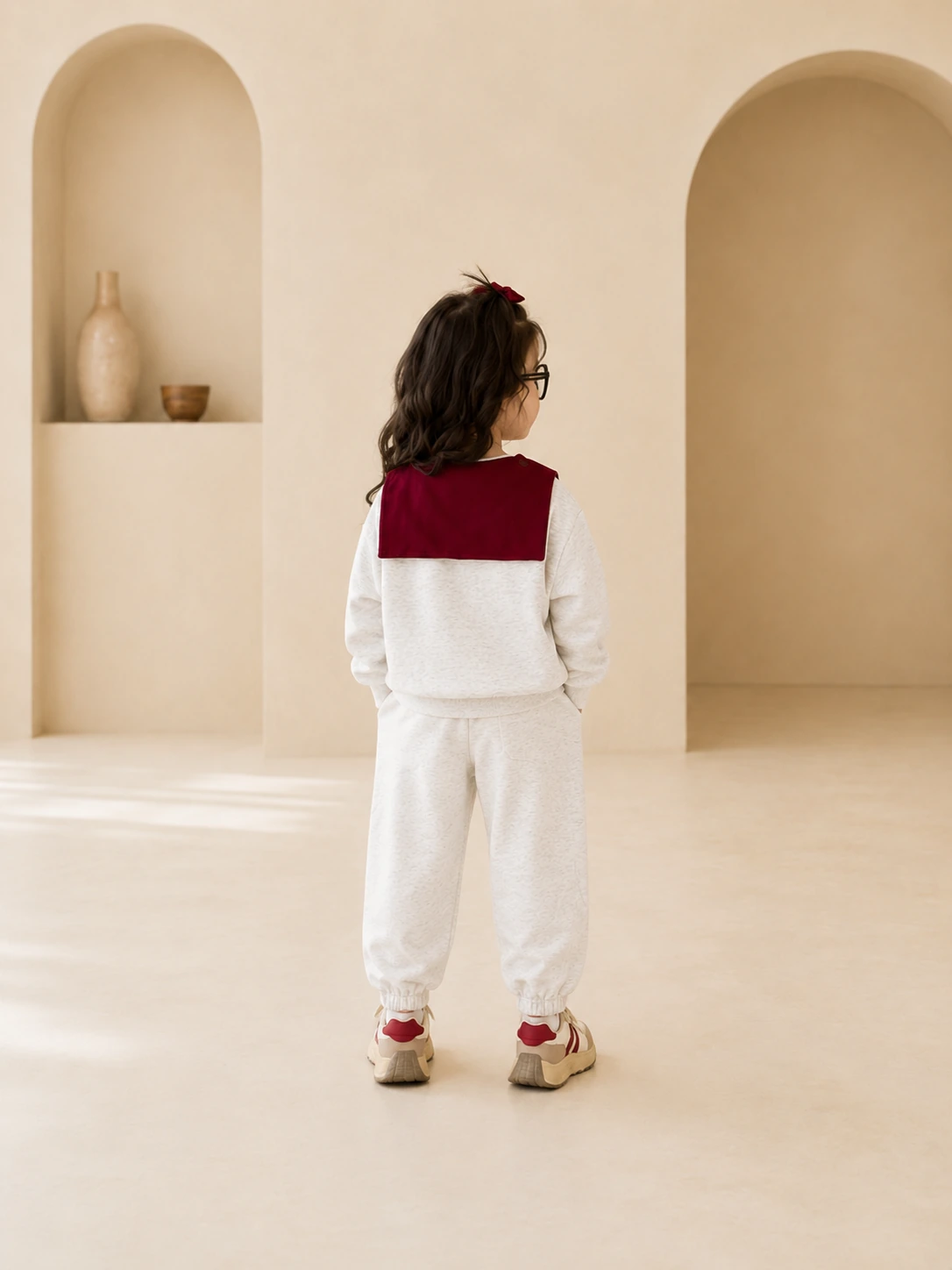 Girl wearing a cream sweatshirt and jogger set with burgundy scarf detail